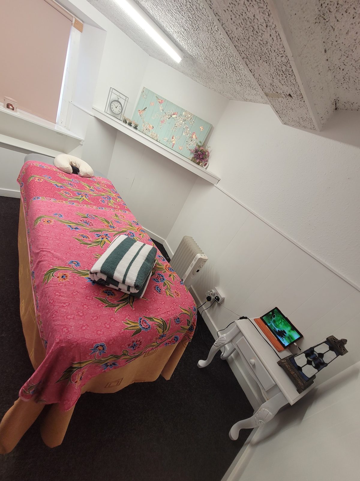 A massage bed with a pink Thai-print cover, ready for a treatment